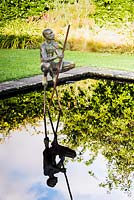 Sculpture of a naked man crouching on a reflecting pool 
