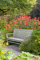 A wooden bench in The Lanhydrock Garden, noted for its hot colours, at Wollerton Old Hall Garden, near Market Drayton, Shropshire.
