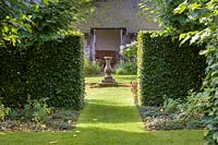 The view through the various garden rooms to the sundial in the Sundial Garden at Wollerton Old Hall Garden, near Market Drayton, Shropshire. Planting includes beech hedging and lime trees.