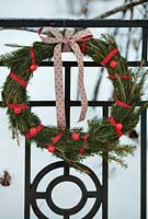 Winter decorations - simple wreath in red and green hanging on metal gate