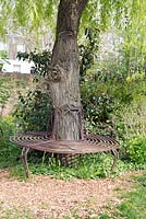 Decorative circular metal seat or bench around the base of a tree. Culpeper Community Garden, London Borough of Islington.