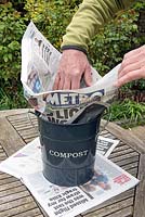 Man lining compost bin with free newspaper.
