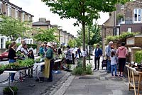People buying plants from community plant stall in urban street, Wilberforce Road Gardeners plant sale, London Borough of Hackney.