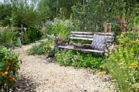 Wooden bench and flower and vegetable borders along gravel path - The BBC Spring Watch Garden - RHS Hampton Court Festival 2019.