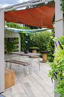 Outdoor room with removeable canvas canopy roof, plant screen, table and chairs and planting of herbs and vegetables, with Nasturtiums and climbing french beans - The Year of Green Action Garden - RHS Hampton Court Palace Garden Festival 2019. Sponsors: Defra.