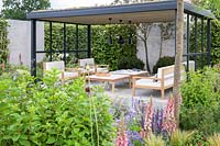 Timber table and chairs on slab patio -The Viking Cruises Lagom Garden - RHS Hampton Court  Palace Garden Festival 2019  - Designer: Will Williams
