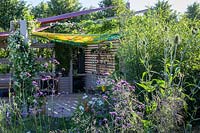 Outdoor room with removeable canvas canopy roof, plant screen and planting of herbs and vegetables, with Nasturtiums and climbing french beans - The Year of Green Action Garden - RHS Hampton Court Palace Garden Festival 2019 - Designers: Helen J Rosevear and Jane Stoneham - Sponsors: Defra.
