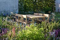 Timber table and chairs on slab patio - The Viking Cruises Lagom Garden - RHS Hampton Court  Palace Garden Festival 2019.