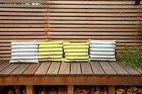 London contemporary garden -  lower wood deck area with  wooden seat and cushions