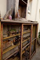 Old timber cabinet with cracked, peeling paint being used to display a collection of bric a brac.