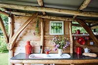 Rustic timber kitchen hut with view of sink and kitchen surface.
