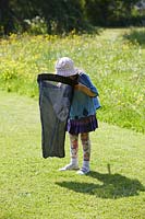Young girl checking net for captured insects.