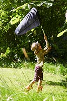Young boy trying to catch insects in net.