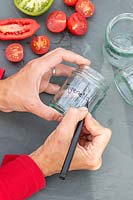 Woman using marker pen to write name on jam jar