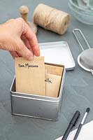 Woman placing a labelled brown envelope with seeds into a metal box for safe storing