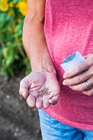 Woman pouring seeds into hand from packet.
