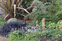 Phormium, Fuchsia, Geranium, Liriope and Ophiopogon surrounding a small sunken pond in suburban garden
