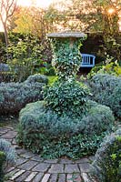 Circular patio with stone urn covered with ivy.