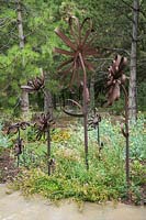 Handcrafted metal flowers under Pinus nigra - Austrian Pine - with groundcover