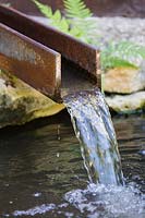 Metal rill, discharging water into a pond, close up detail
