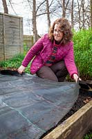 Covering a bed in the vegetable garden with black sheeting to warm the soil and prevent weeds