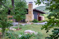 Grass garden with modern building in woodland at Mill Creek Ranch in Vanderpool, Texas designed by Ten Eyck Landscape Inc, July.