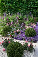 Purple and pink themed border with buxus topiary balls in the 'Tesco Every Little Helps Garden' at BBC Gardener's World Live 2018.