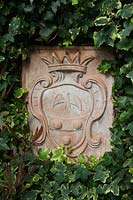 Terracotta coat of arms set among common Ivy.