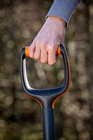 Hand on spade handle. 
