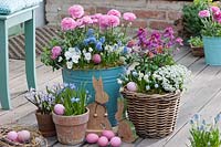 Pots, baskets and buckets planted with spring-flowering plants decorated with easter ornaments. 