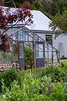A traditional nursery glasshouse with double doors open for ventilation 