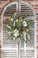 Finished white themed wreath with feathers hanging on vintage shutters