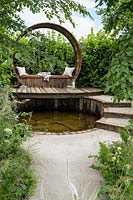 Wooden seating deck with cushions above pond - Stop and Pause Garden - RHS Hampton Court  Palace Garden Festival 2019  