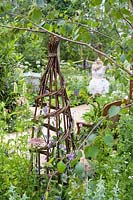 Hand-woven willow obelisk to support flowering sweet peas - Lathyrus odoratus. The Naturecraft Garden. RHS Hampton Court  Palace Garden Festival, 2019.   