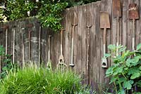 Vintage garden tools hung on a wooden fence