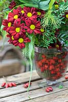 Floral arrangements with red Chrysanthemum and mixed foliage, vases with rosehips in water