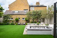 View from the house to modern urban garden with white seating area. 