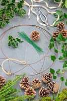 Materials and tools ready for making a natural wreath with cones, yew, moss, ivy and holly