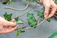 Woman adding Ivy to a thin metal wire wreathg