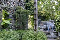 Ruin Garden at Chanticleer showing stone pool and fountain with marble heads, rain chain planted with succulents and foliage plants