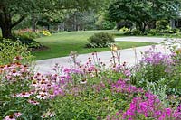Driveway is framed with Hemerocallis, Echinacea and other sun-loving perennials. Expansive lawn, shade borders and home in distance