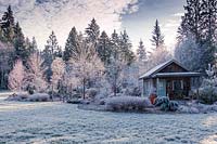 Frosty scene of cabin in large country border with lawn and trees 
