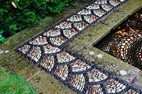 Corner of pond edge with pebble mosaic pattern