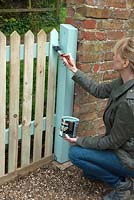 Woman painting a picket fence