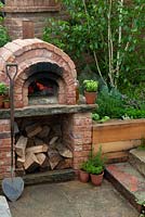 Outdoor brick oven set into raised border with stone steps leading down to it - RHS Malvern Spring Festival