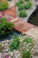 Path of mixed paving slabs over running stream with alpine plants in gravel and stones - RHS Chelsea Flower Show