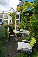 A small greenhouse on a London roof terrace. A small table and deck chair
