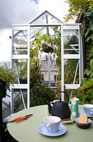 Small table set for tea with a  greenhouse on roof garden in London 