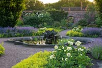 The Walled Garden. The Magnolia Fountain, created by Tom Leaper. A circular pond is surrounded by beds of dahlias, alchemilla mollis and catmint. Arley Hall, Cheshire, UK.