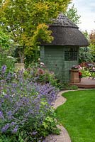 A brick edging separates the lawn from an herbaceous border of catmint, roses, ammi, hardy geraniums and alliums, leading to summerhouse and deck.